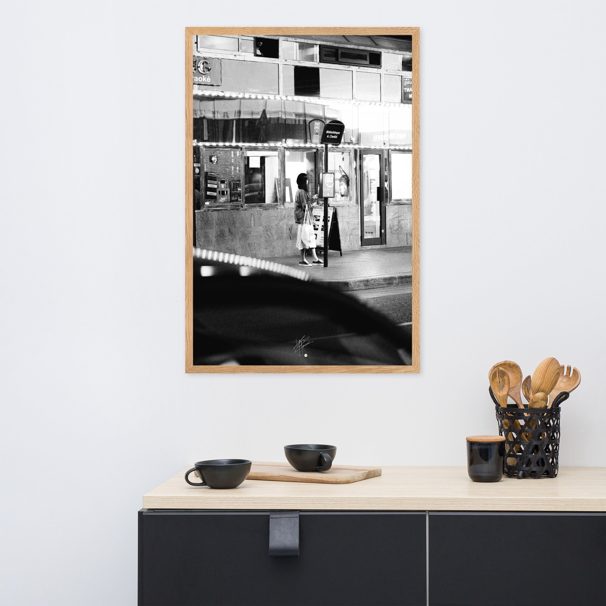 Photographie en noir et blanc d'une femme éclairée par son téléphone dans une rue sombre, mettant en évidence le contraste lumineux de la scène urbaine.