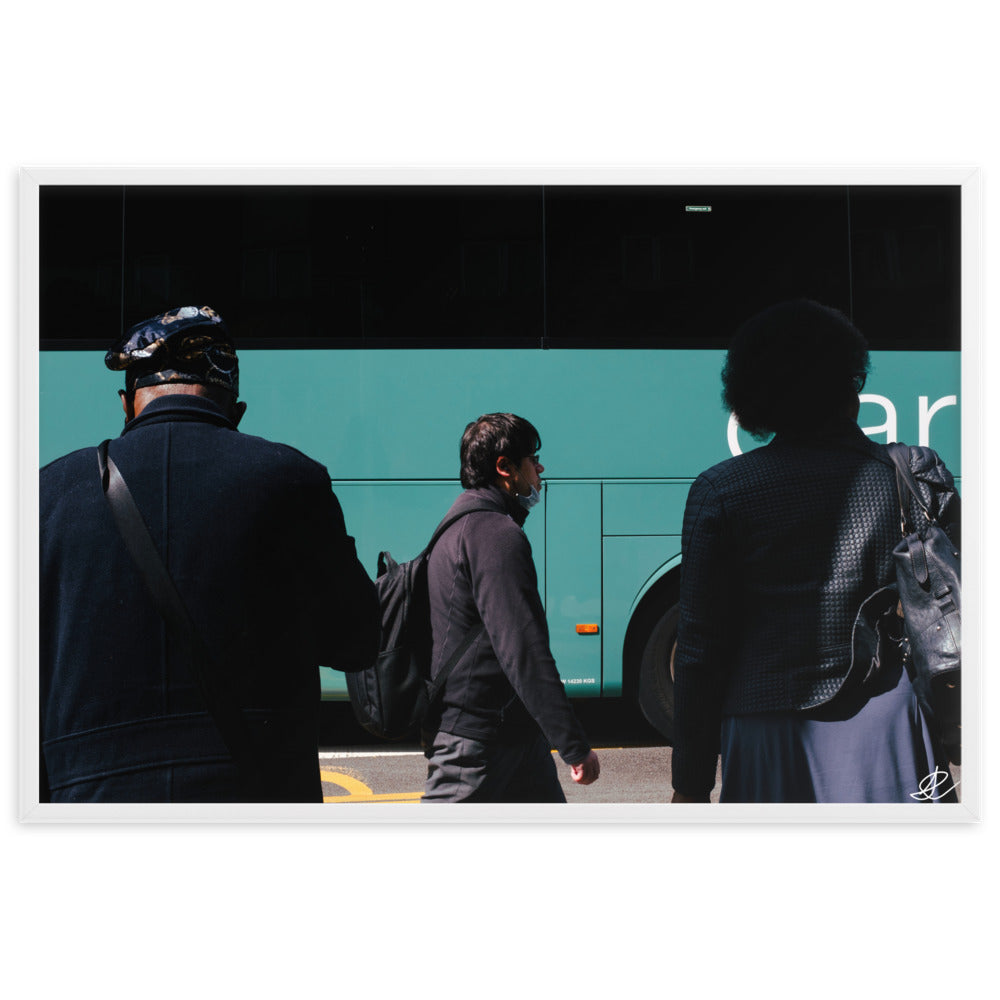 Photographie encadrée 'Arrêt de Bus' par Ilan Shoham, illustrant une scène urbaine londonienne riche en narratif, avec deux individus au premier plan, un passant solitaire au second, et un bus flou en arrière-plan, symbolisant la complexité et la beauté du quotidien.