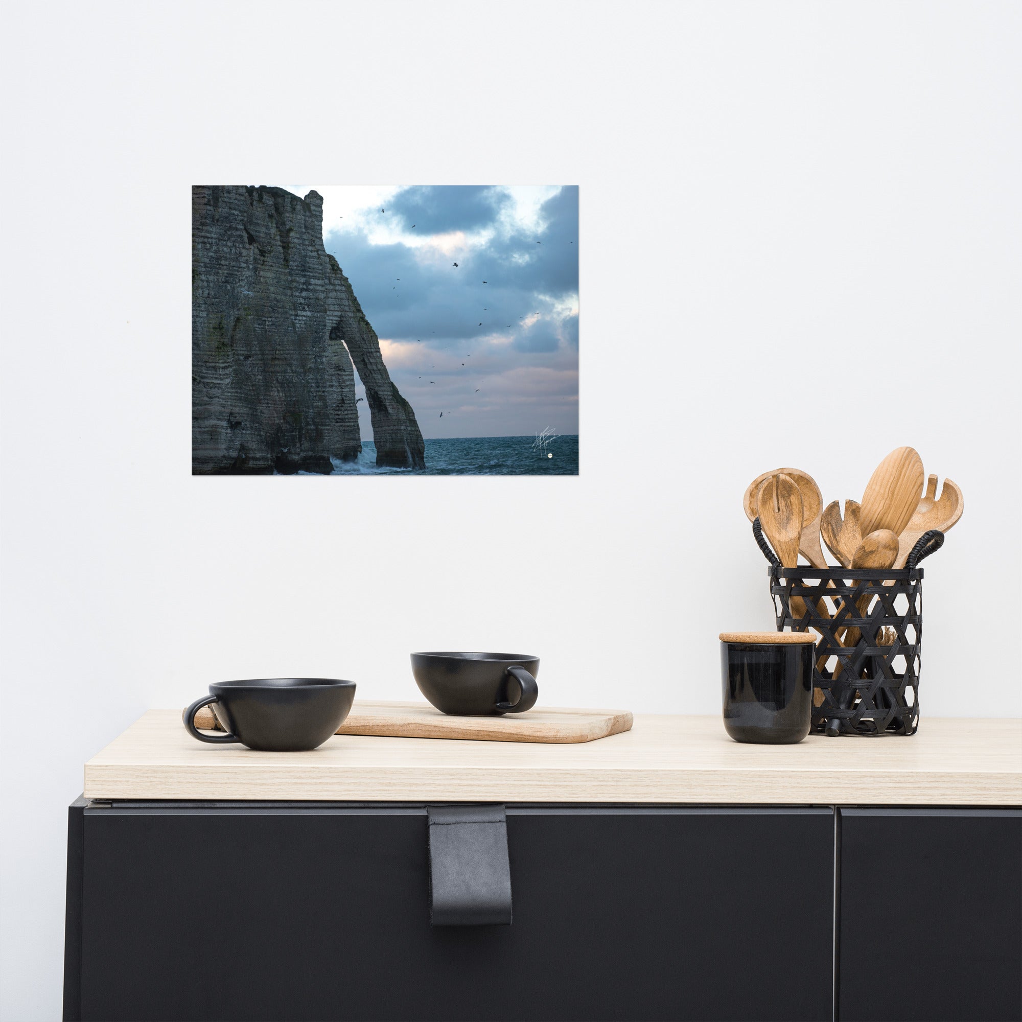 Vue panoramique des falaises d'Étretat avec des vagues s'écrasant puissamment sur la côte, sous un ciel nuageux où les mouettes virevoltent, incarnant la beauté sauvage de la Normandie.