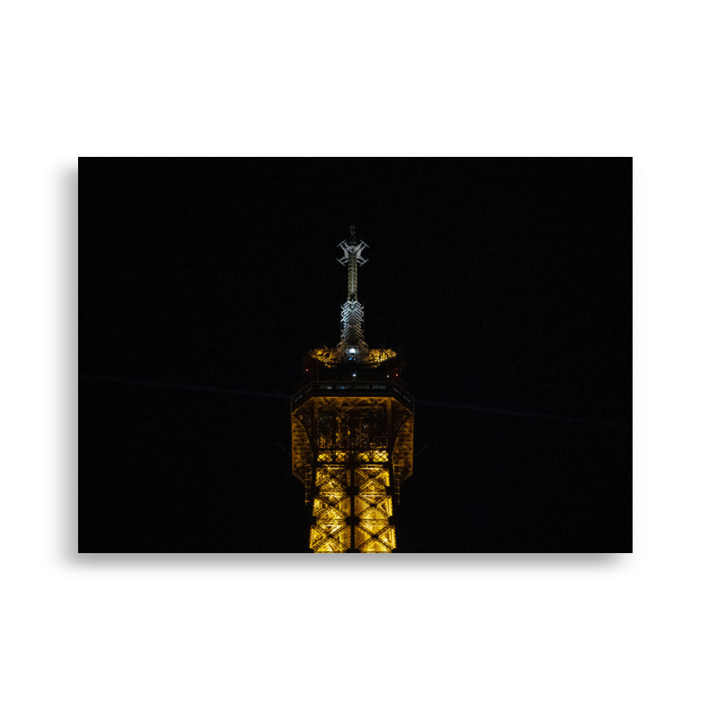 Photographie 'L'antenne' de la partie supérieure de la Tour Eiffel illuminée de nuit.