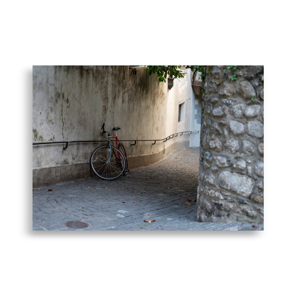 Photographie d'une rue pavée en descente de Genève, sans voitures, avec un vélo non attaché au premier plan. L'atmosphère est paisible et le coucher de soleil ajoute une teinte chaude à la scène.